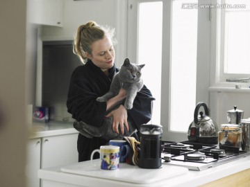 女子抱着猫站在厨房