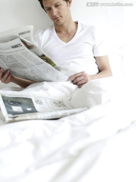 年轻人在床上看报纸