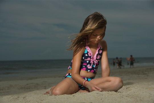 伤心的小女孩坐在沙滩