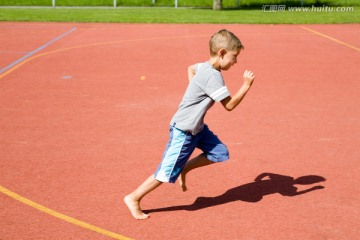 男孩在运动场上赤脚跑