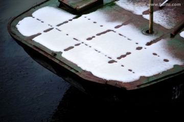 长满水草的河上积雪的船头特写