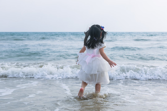海边玩耍的小女孩背影