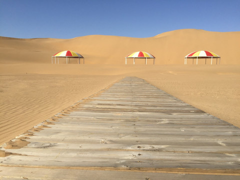 沙漠中的木栈道与遮阳伞