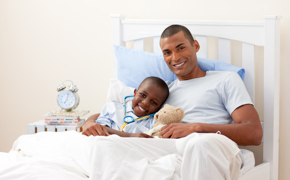 微笑的父亲和孩子躺在床上