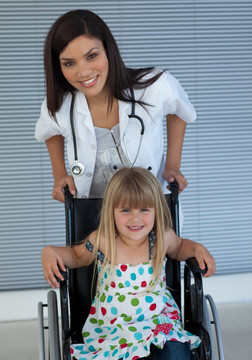 年轻医生扶着坐在轮椅上的女孩