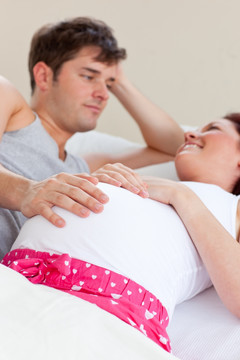 幸福孕妇和丈夫躺在床上