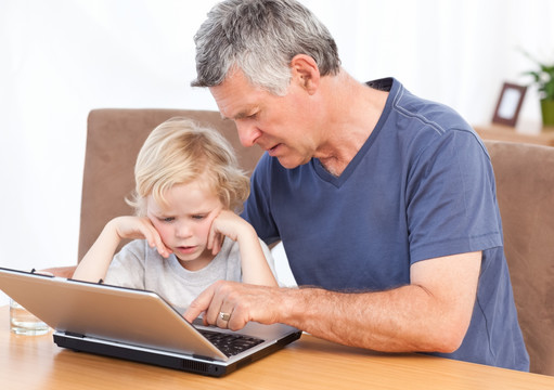 小男孩和祖父一起玩笔记本电脑