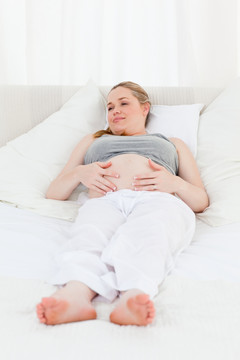 在床上抚摸自己肚子的孕妇