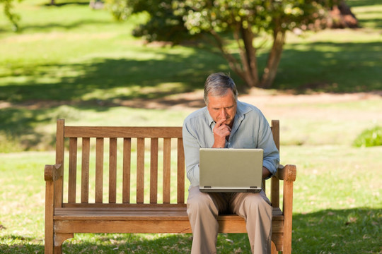 老人在公园里用笔记本电脑