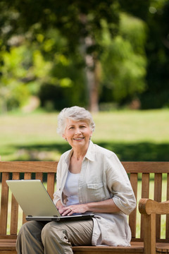 老奶奶坐在长椅上玩电脑