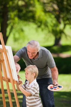 祖父和他的孙子在花园里绘画