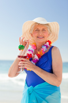 在海滩上喝鸡尾酒的老妇人