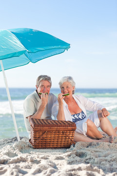 老夫妇坐在沙滩上吃西瓜