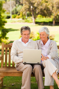 公园里一起玩笔记本电脑的老夫妇