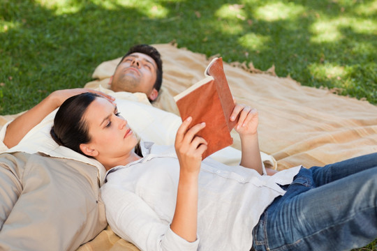 公园里靠在男友身上看书的女人