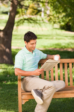 坐在公园长椅拿着报纸杯子的男人