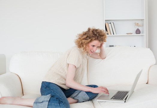 金发女人坐在沙发上使用电脑