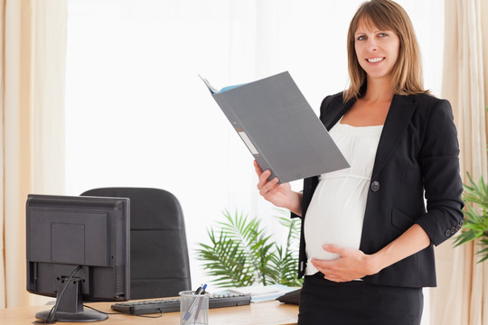 孕妇在办公室拿着一个文件夹