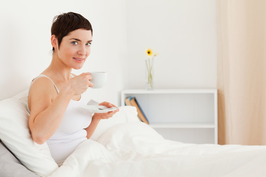 在床上喝咖啡的美丽女人