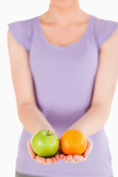 手拿苹果和橙子的女人