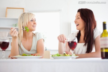 两个女人在吃沙拉并喝着酒