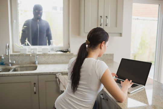 小偷透过窗户观察正在上网的女人
