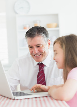 父亲在教女儿使用笔记本电脑