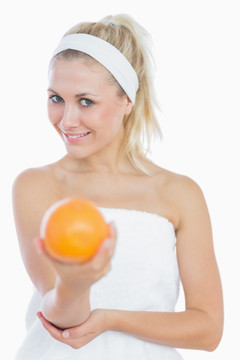 裹着浴巾的美丽女人拿着橙子