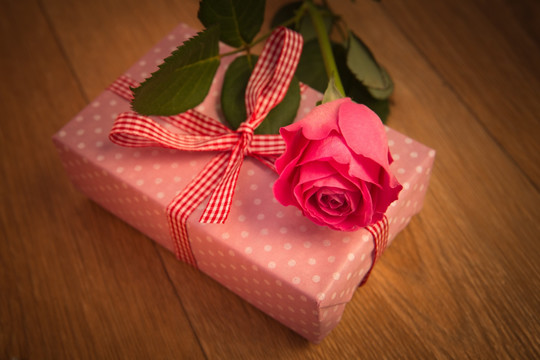 一束粉色的玫瑰放在礼物盒上
