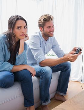 女人坐在玩电子游戏的男子旁边