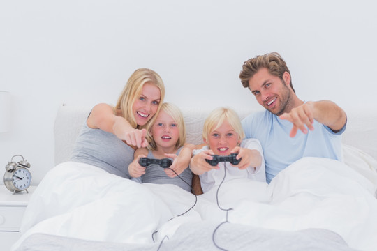 坐在床上的一家人玩电子游戏