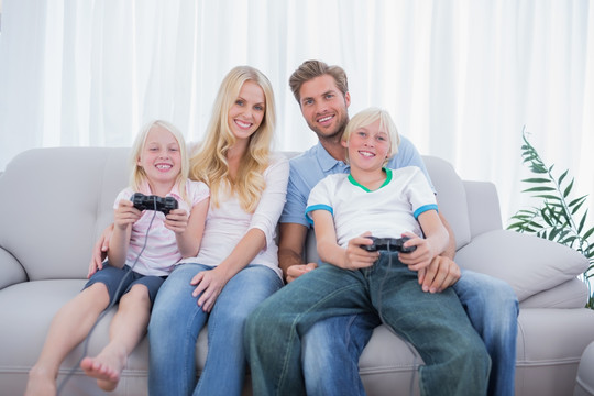 一家人坐在沙发上玩电子游戏
