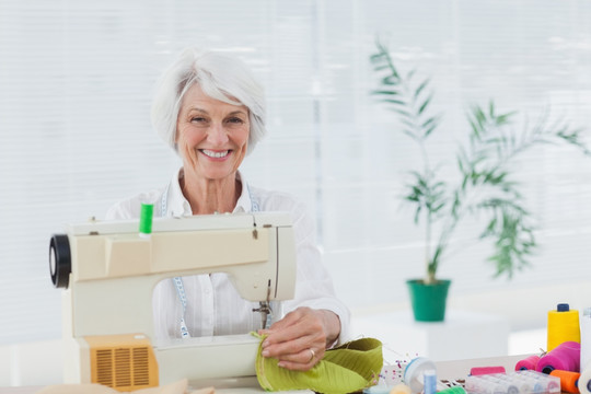 快乐的女人在家里使用缝纫机