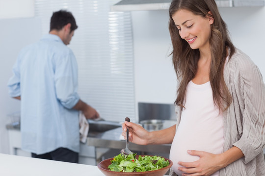 孕妇在厨房里搅拌一份沙拉