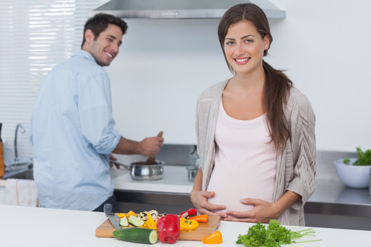 孕妇抱着她的肚子在厨房里