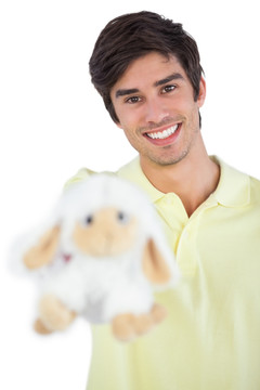 男人微笑着拿着绵羊玩具
