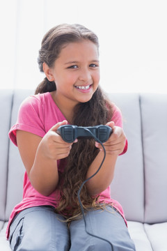 坐在沙发上的小女孩玩电子游戏