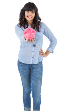 年轻的女人展示她小猪储钱罐
