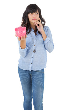 年轻的女人拿着小猪储钱罐