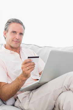 男子在沙发上使用电脑网上购物