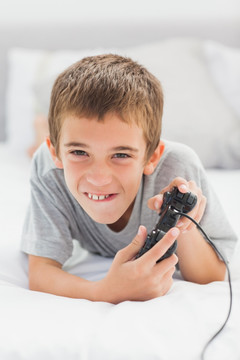 小男孩在床上玩电子游戏