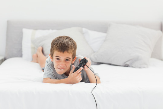 小男孩在床上玩电子游戏