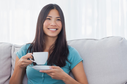 坐在沙发上喝一杯茶的女人