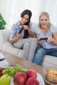 坐在沙发上玩电子游戏的女人