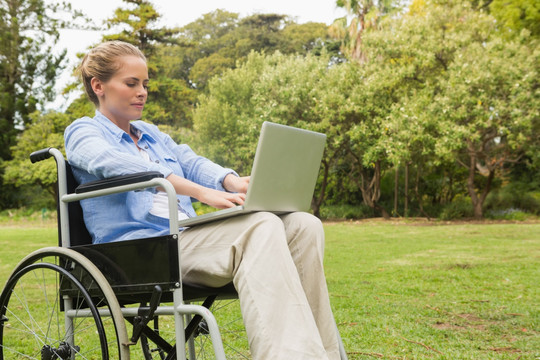 女人坐在轮椅上使用笔记本电脑