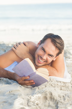 英俊男子在海滩上看书
