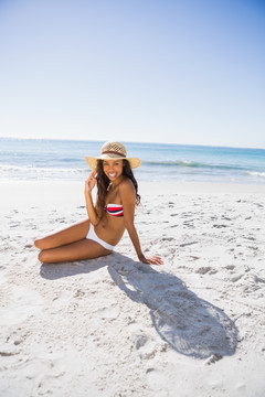 戴着太阳帽坐在沙滩上的女人