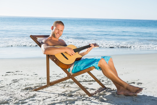 坐在沙滩椅上弹吉他的男人