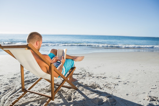 坐在沙滩椅上看书的男人