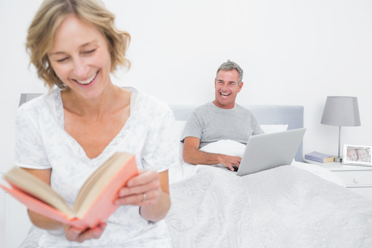 在卧室看书的女人和用电脑的丈夫
